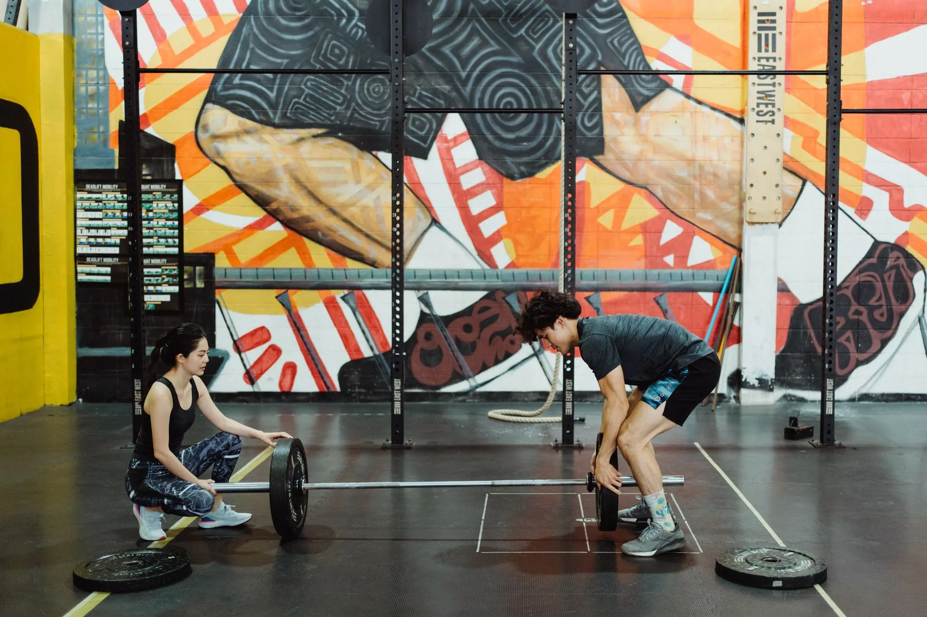 Two athletes with a barbell in a representative training space